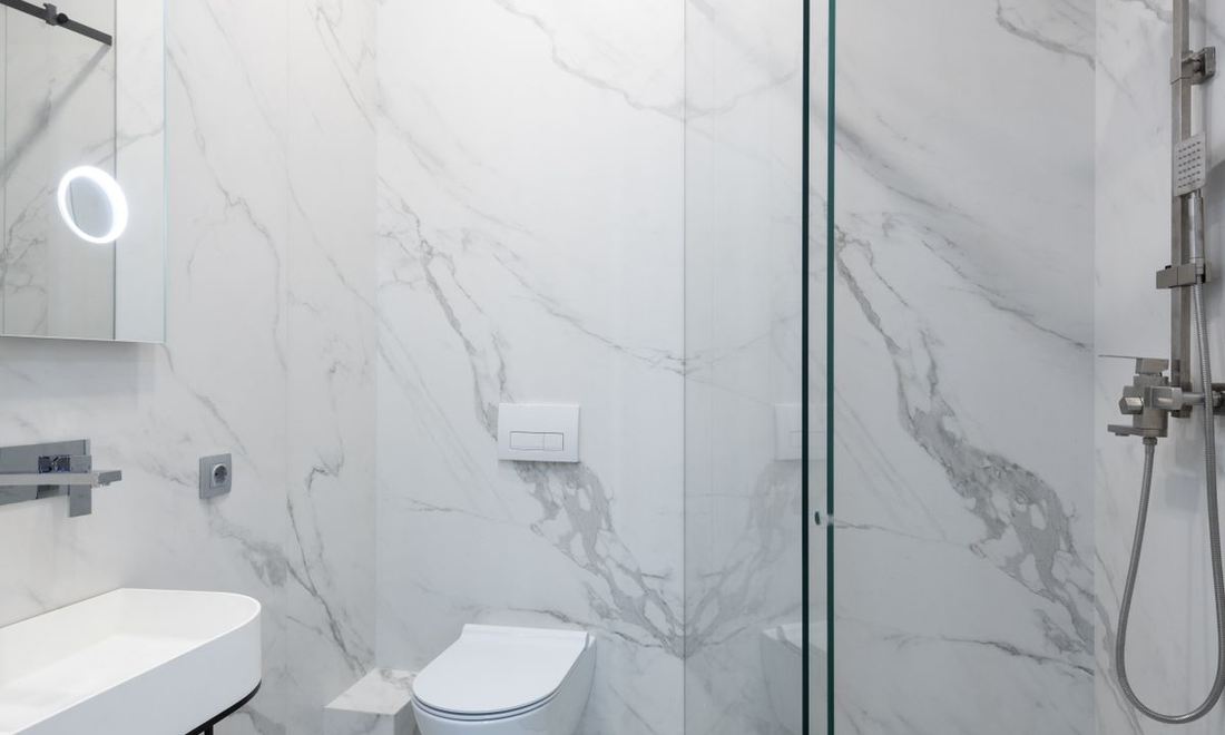 A finished bathroom remodel with marble tile and a glass shower enclosure